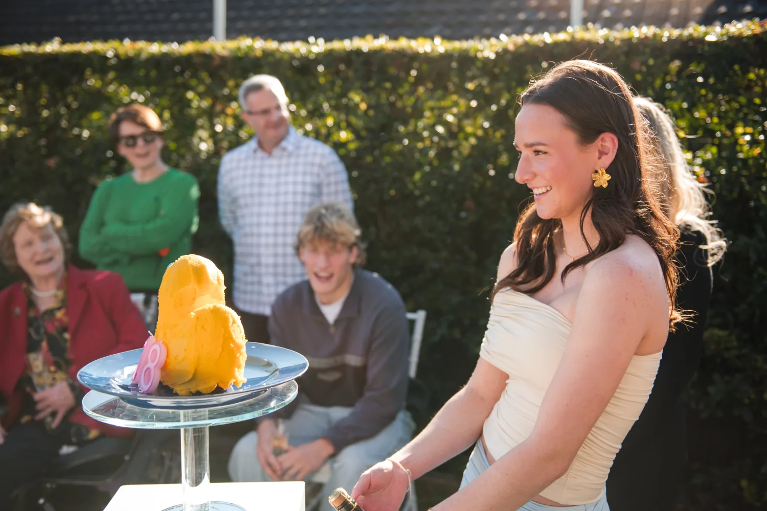 Anna smiling beside her birthday cake as family watch
