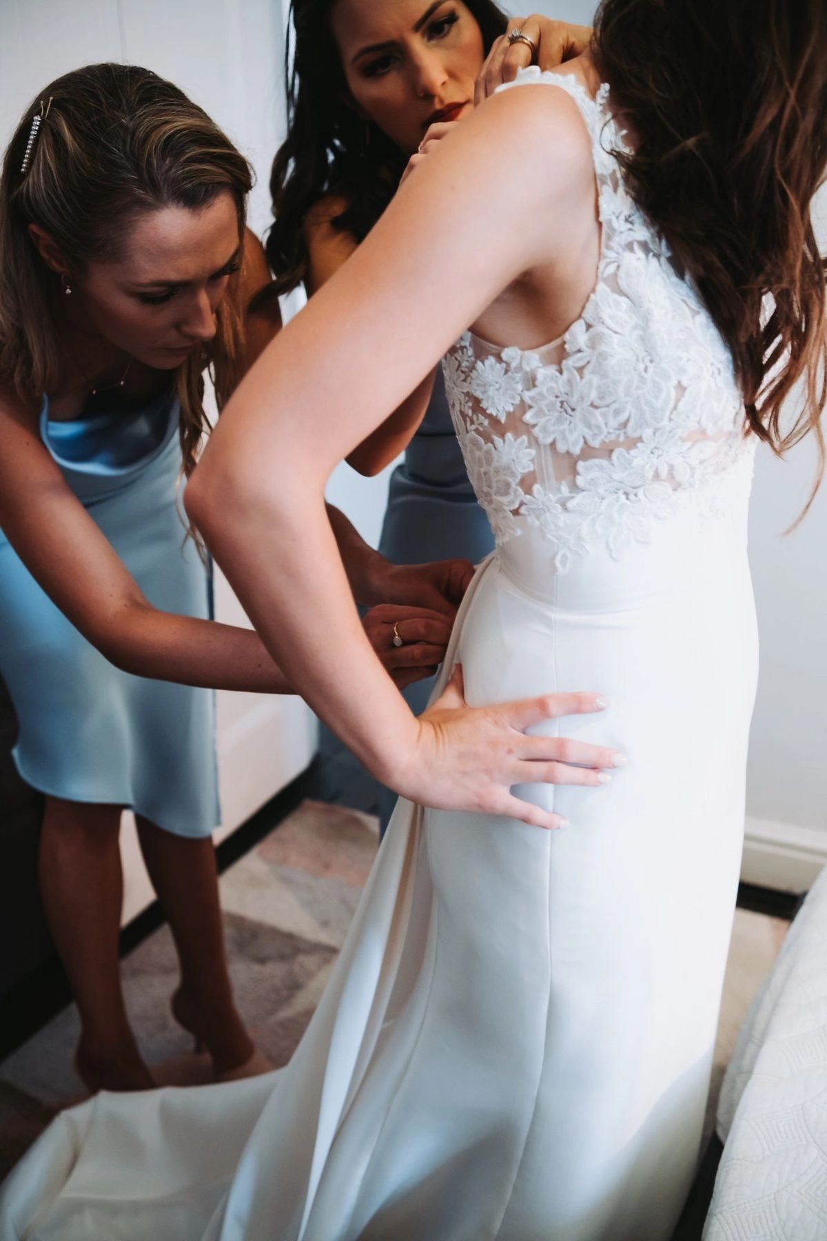Lillie having the back of her wedding dress fastened while getting ready